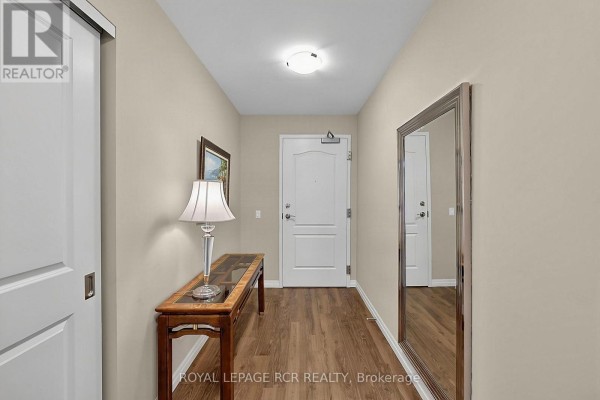 Apartment entryway with wood-look flooring, console table, and large mirror. - 318 - 460 William Graham Drive, Aurora