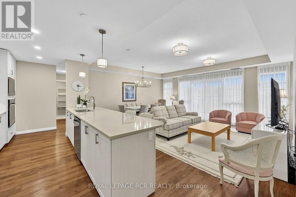 Open concept living and dining area with sofa, armchairs, coffee table, and dining set. - 318 - 460 William Graham Drive, Aurora