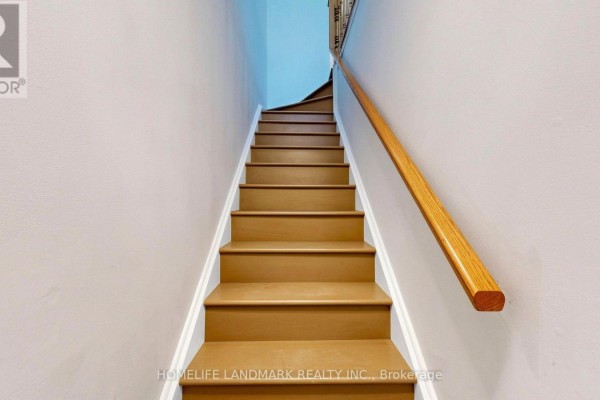 Interior view looking up a wooden staircase with a light-colored handrail and beige carpeted steps. - 318 - 75 Weldrick Road E, Richmond Hill