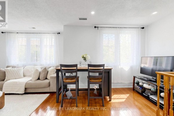 Living area with a sofa, two chairs at a counter, and a television on a stand. - 318 - 75 Weldrick Road E, Richmond Hill