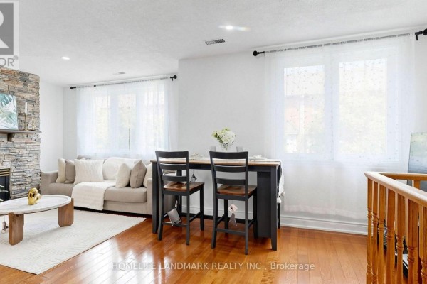 Living area with a sofa, fireplace, two chairs at a counter, and a television on a stand. - 318 - 75 Weldrick Road E, Richmond Hill