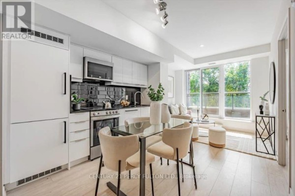 Open concept kitchen and living area with dining table, sofa, and large windows. - 318 - 90 Glen Everest Road, Toronto