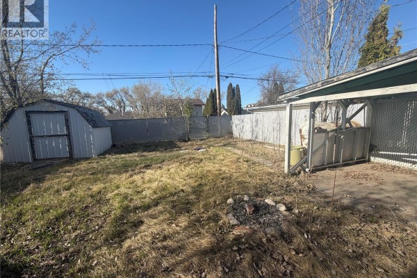 Kitchen with oak cabinets, double sink, and white microwave above stove. - 318 25th Street E, Prince Albert