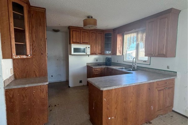 Basement recreation room with brick fireplace and exposed support column. - 318 25th Street E, Prince Albert