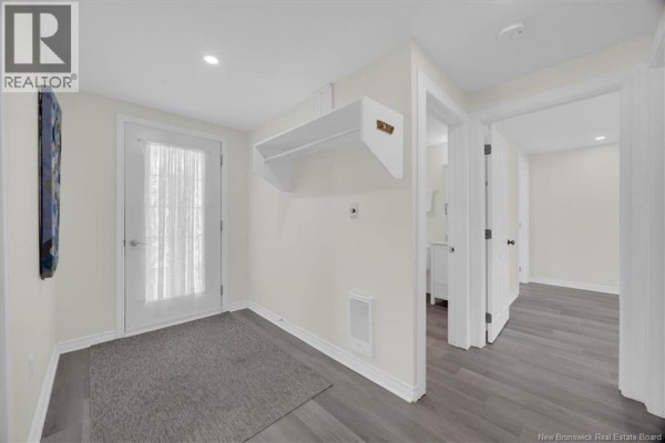 Interior hallway with a glass door, grey rug, white walls, and grey wood-look flooring. - 318 Parr Street, Saint Andrews