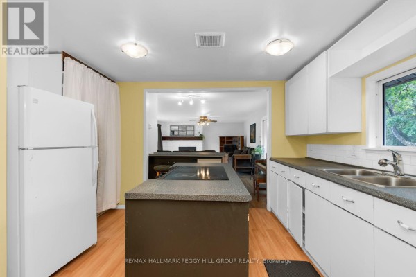 Kitchen with white cabinets, a dark island with a stovetop, and a view of the living room. - 318 Percy Street, Tay