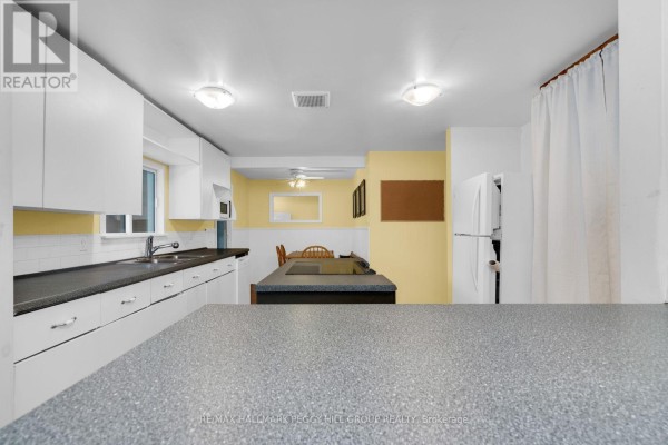 Kitchen with white cabinets, dark countertops, and a view of the dining area and hallway. - 318 Percy Street, Tay