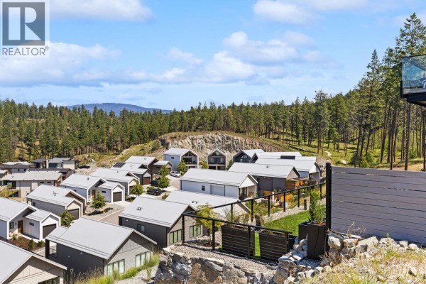 Aerial view of a neighborhood with modern houses, some on steep slopes, surrounded by trees. - 3183 Hilltown Drive, Kelowna