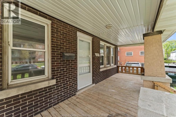 Close-up view of the covered porch, showing the brick exterior, wooden floor, and front door. - 3185 Donnelly, Windsor