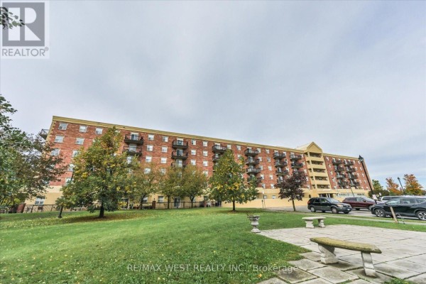 Exterior view of a long brick apartment building with balconies and surrounding green space. - 319 - 7373 Martin Grove Road, Vaughan