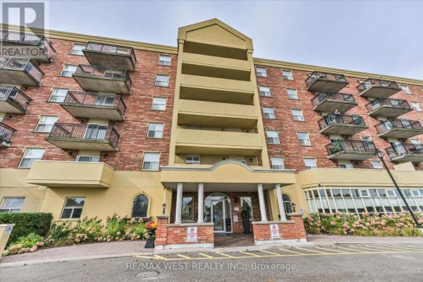 Main entrance of a brick apartment building with a yellow facade and columns. - 319 - 7373 Martin Grove Road, Vaughan