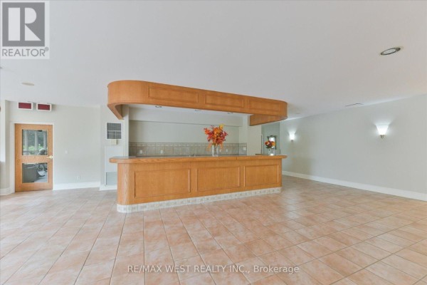 Spacious lobby with tiled floors, neutral walls, decorative mirror, and potted plants. - 319 - 7373 Martin Grove Road, Vaughan