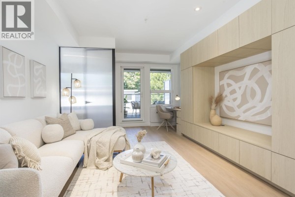 Living room with built-in light wood cabinetry and abstract art above the sofa. - 319 2471 St. George Street, Vancouver