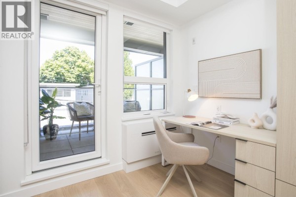 Home office space with a desk, chair, and large window overlooking a balcony. - 319 2471 St. George Street, Vancouver
