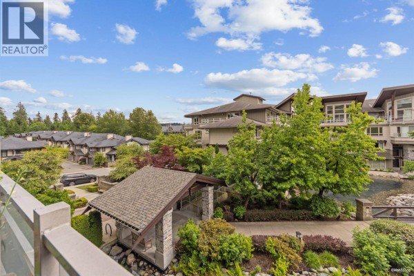 View of apartment buildings and manicured landscaping with stone walkways and a covered entrance. - 319 580 Raven Woods Drive, North Vancouver