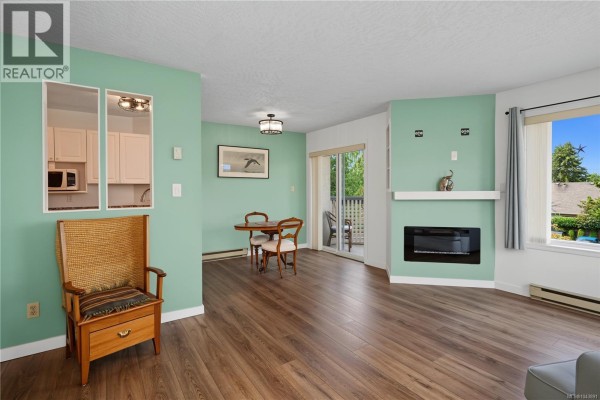 Spacious living and dining area with a sofa, vintage side table, and view into the kitchen. - 319 9882 Fifth St, Sidney