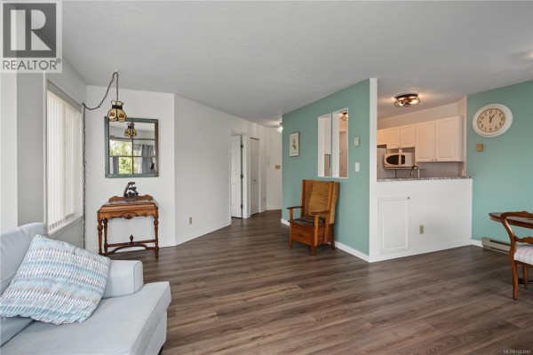 Dining nook with an oval wood table, two chairs, and a sliding glass door to a balcony. - 319 9882 Fifth St, Sidney
