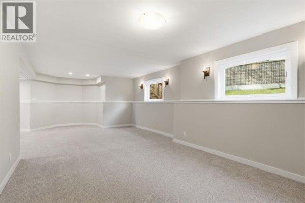 Open concept living area with vaulted ceiling, natural light, wood-look flooring, and glass door to the deck. - 319 Citadel Hills Place Nw, Calgary