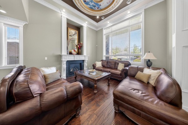Living room with two brown leather sofas, a chaise, a coffee table, and a fireplace with a white mantle. - 31920 Glenwood Avenue, Abbotsford