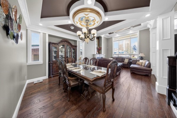 Formal dining room with a large wooden table, chairs, a china cabinet, and an adjacent living room area. - 31920 Glenwood Avenue, Abbotsford