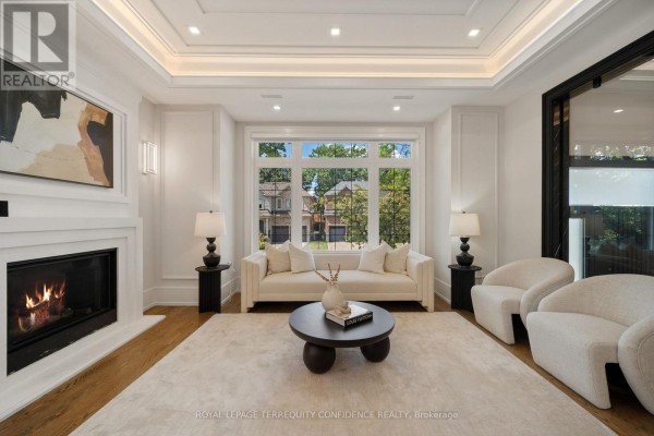 Living room with a large bay window, white sofa, armchairs, and fireplace. - 319b Horsham Avenue, Toronto