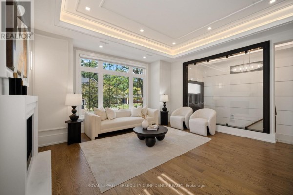 Living room showing a fireplace, sofa, armchairs, and view of modern staircase with glass railing. - 319b Horsham Avenue, Toronto