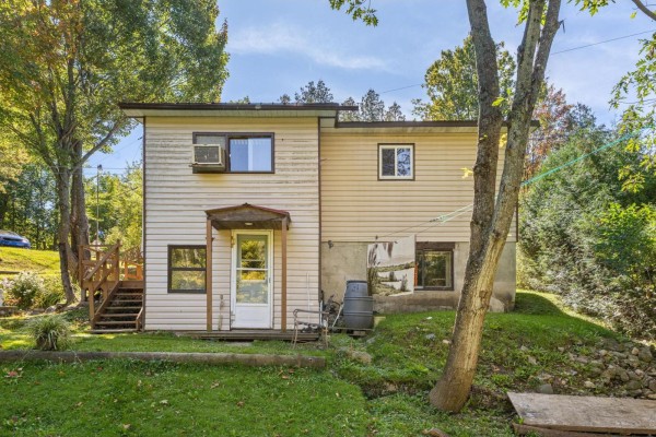 Side view of a duplex with beige siding, windows, a door, and surrounding trees. - 31a-31b Ch. Du Boisé, Val Des Monts