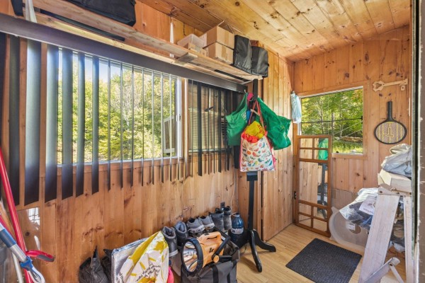Interior of a sunroom with wood paneling, windows, and storage items. - 31a-31b Ch. Du Boisé, Val Des Monts