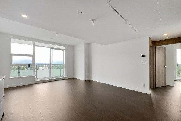 Living area with dark wood floors, white walls, large windows, and a doorway. - 31xx 13778 100 Avenue, Surrey