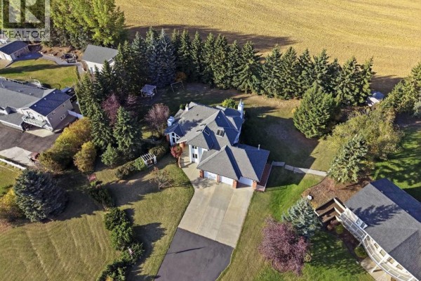 Living room with vaulted ceiling, large windows, fireplace, and beige leather sofas. - 32, 28364 Township Road 384, Rural Red Deer County