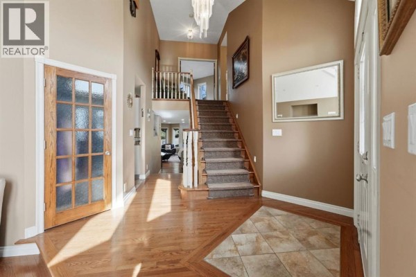 Living room with a fireplace, large windows, dining area, and beige leather seating. - 32, 28364 Township Road 384, Rural Red Deer County