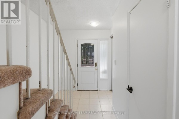 Interior view of townhouse foyer with tiled floor, white walls, and staircase. - 32 - 11 Livonia Place, Toronto