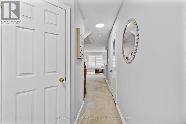 Hallway with white doors, a round mirror, and a view into a living area. - 32 - 130 Robert Street, Milton