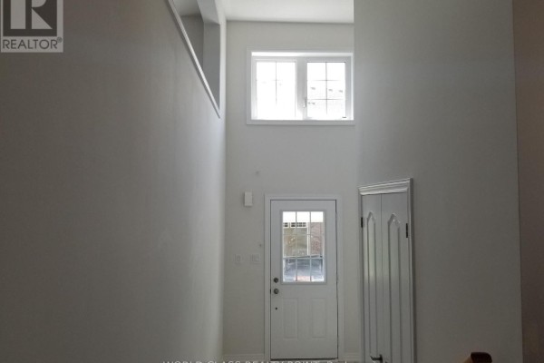 Bright interior entryway of a townhouse with a glass-paneled front door and a large window above. - 32 - 470 Linden Drive, Cambridge