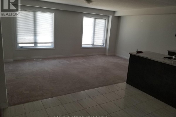 Living room area with two large windows, beige carpet, and a granite countertop island. - 32 - 470 Linden Drive, Cambridge