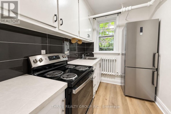Small kitchen with white cabinets, black stove, stainless steel refrigerator, and window. - 32 - 50 Ridout Street S, London South