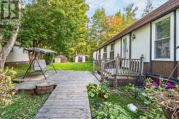 Wooden deck and patio area at the rear of the mobile home, with a swing set and shed visible. - 32 - 7481 Mitch Owens Road, Ottawa
