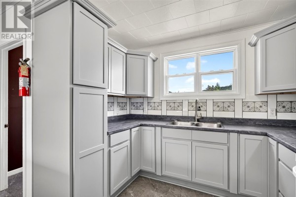 Kitchen with light grey cabinets, grey countertops, and a double sink with a window view. - 32-34 Glam Road, Clarkes Beach