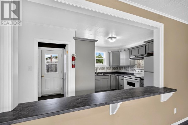 View from living area into the kitchen, showing a pass-through counter and door. - 32-34 Glam Road, Clarkes Beach
