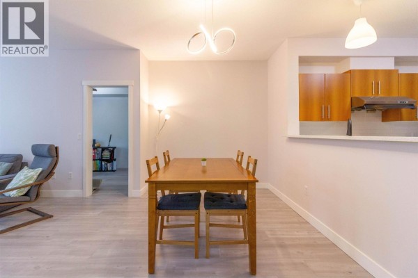 Spacious living room with a large TV, fireplace, and dining area visible in the background. - 32 9229 University Crescent, Burnaby