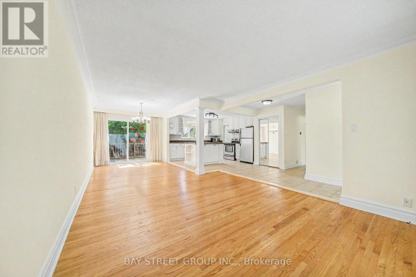 Open concept living and dining area with hardwood floors, white cabinets, and a sliding glass door to the backyard. - 32 Alanadale Avenue, Markham