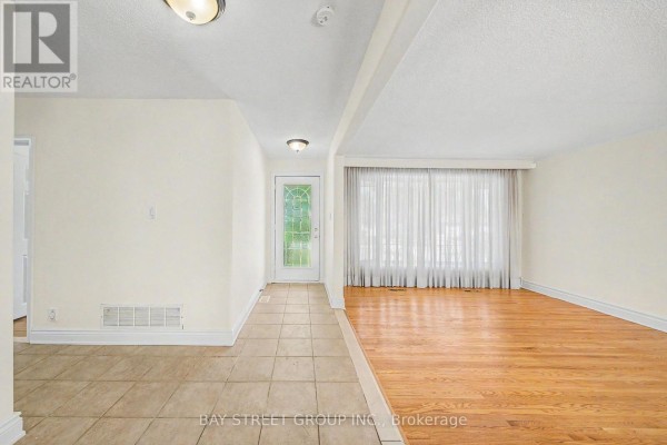 Entrance hallway with tiled flooring and a view of the front door and living room with large windows. - 32 Alanadale Avenue, Markham