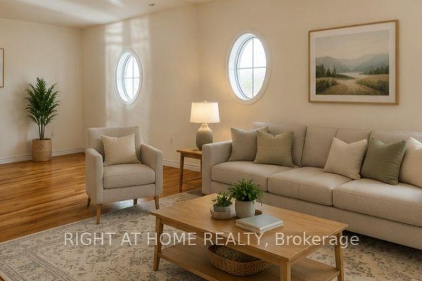 Living room with beige sofa, armchair, wooden coffee table, and oval windows. - 32 Aspen Hills Road, Brampton