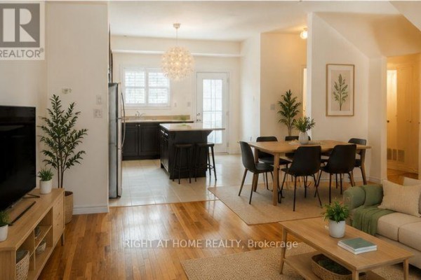 Open concept living, dining, and kitchen area with hardwood floors and modern furniture. - 32 Aspen Hills Road, Brampton