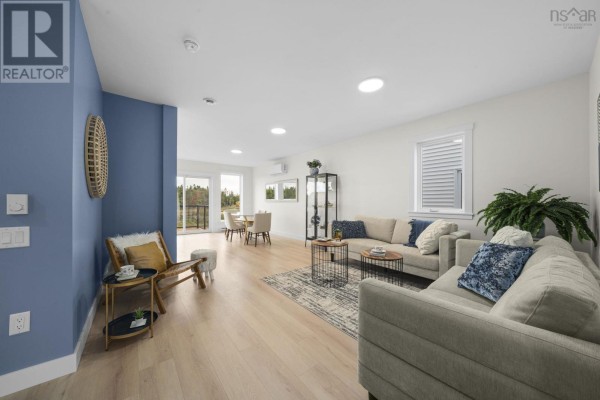 Open concept living and dining area with beige sofas and light wood floors. - 32 Berm Street, Spryfield