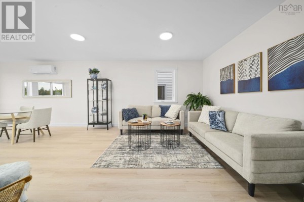 Living room with beige sectional sofas, coffee tables, and art on the wall. - 32 Berm Street, Spryfield