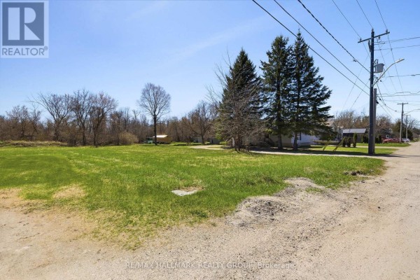 A grassy lot with a two-story house on the left and trees on the right. - 32 Brock Street N, Perth