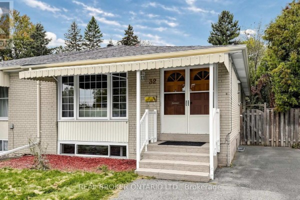 Exterior front view of a light brick bungalow with beige awnings over the windows and double front doors. - 32 Cairnside Crescent, Toronto