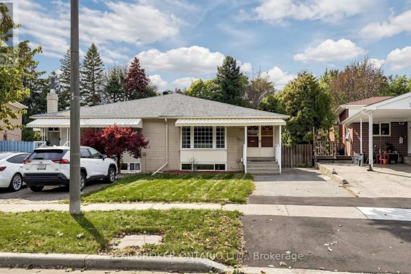 Side view of a light brick bungalow with a driveway, mature trees, and neighboring houses. - 32 Cairnside Crescent, Toronto