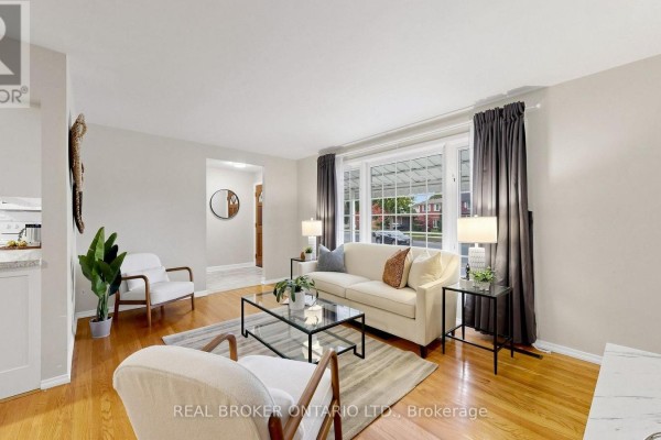 Living room with hardwood floors, beige sofa, two armchairs, glass coffee table, and large window. - 32 Cairnside Crescent, Toronto